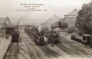 La gare, les voies de chemin de fer, les deux rotondes et les locomotives à vapeur.
